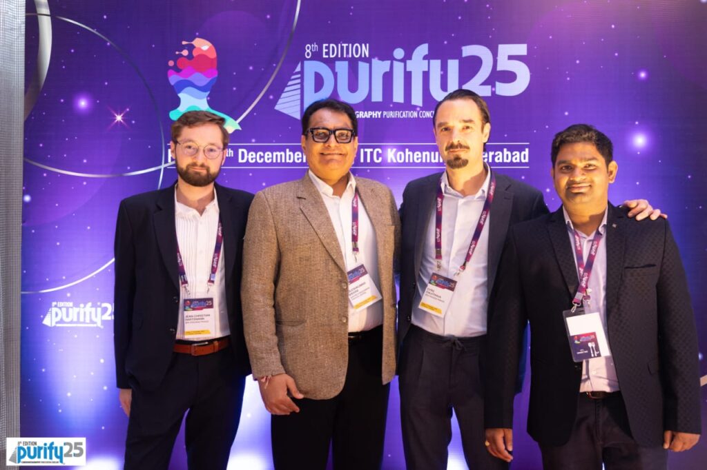 Four delegates with name badges posing before the 8th Edition Purify 25 backdrop at ITC Kohenur, Hyderabad
