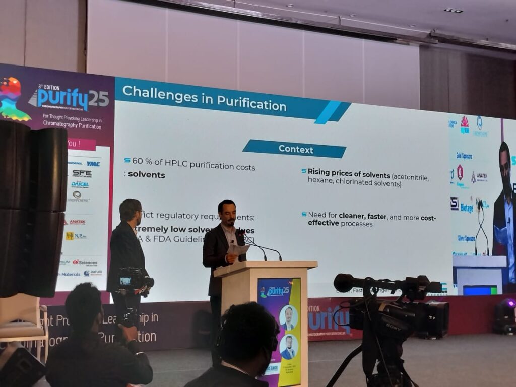 Wide view of a speaker presenting the Challenges in Purification slide on rising solvent prices at Purify 25