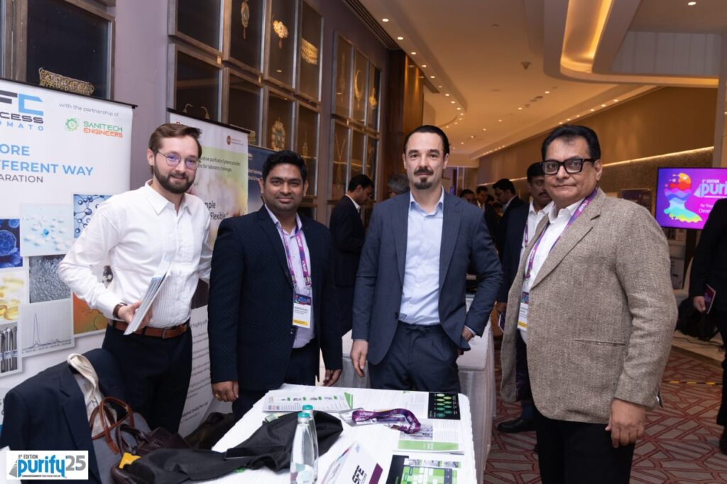 Four delegates posing at the Sanitech Engineers and SFE Process exhibition stall at Purify 25